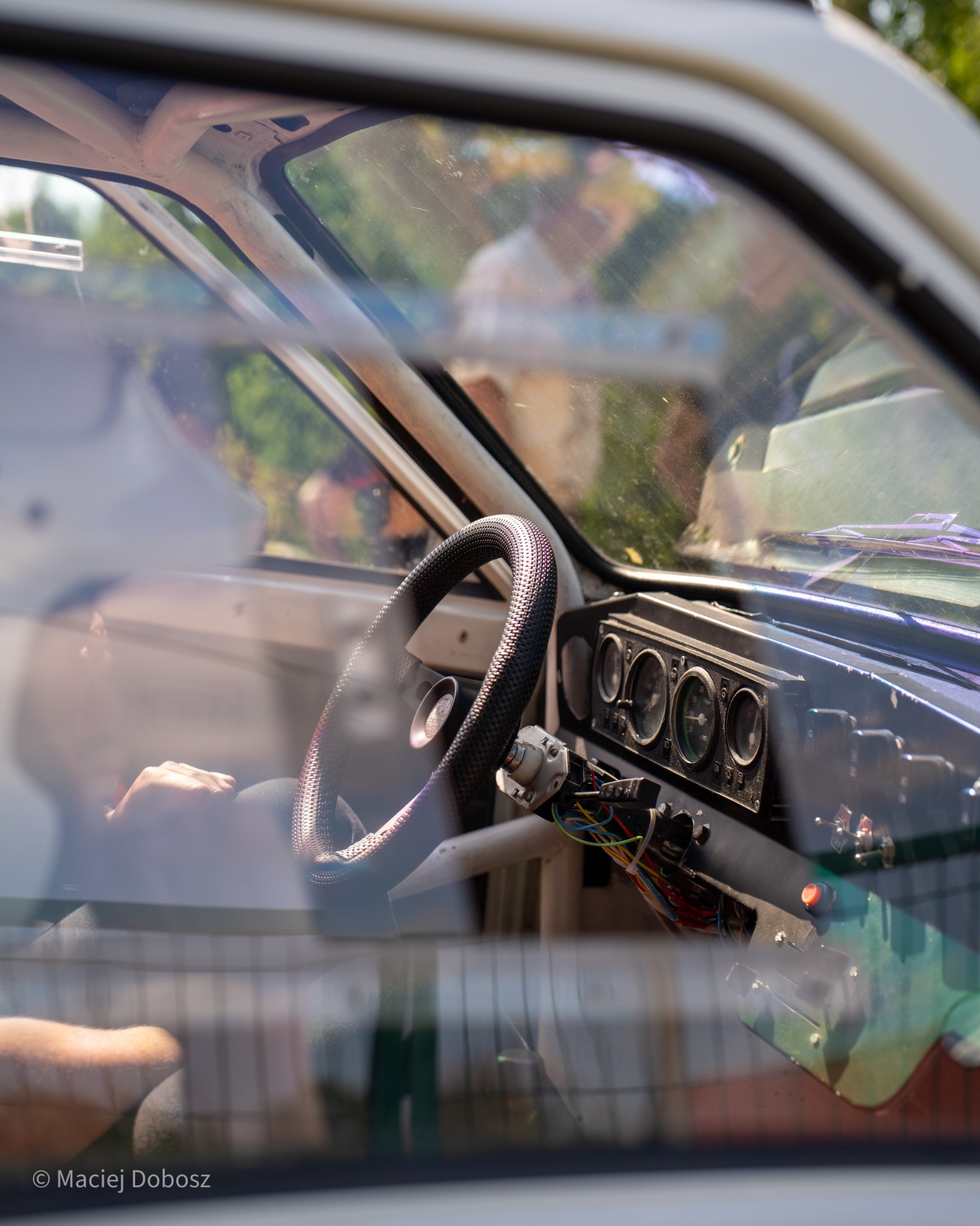 Steering wheel and stripped dashboard seen through a car window